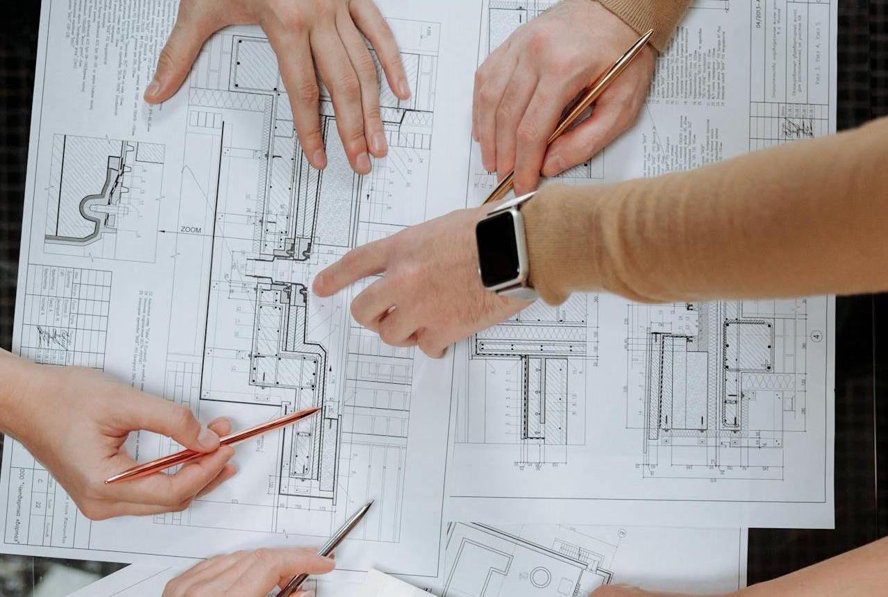 Team reviewing detailed plans and technical drawings, representing disciplined underwriting, analysis, and fundamentals-driven investment decisions