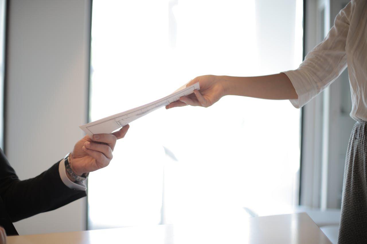 Person handing over a document during a professional exchange, representing transparent reporting, clear disclosure, and verified investment data