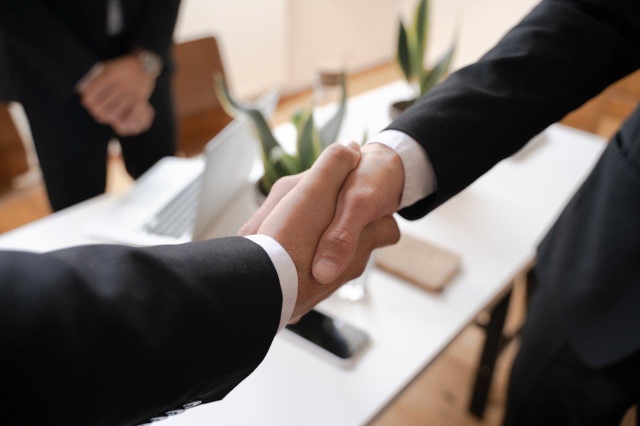 Business professionals shaking hands in an office setting, representing vetted deal sourcing and curated investment opportunities