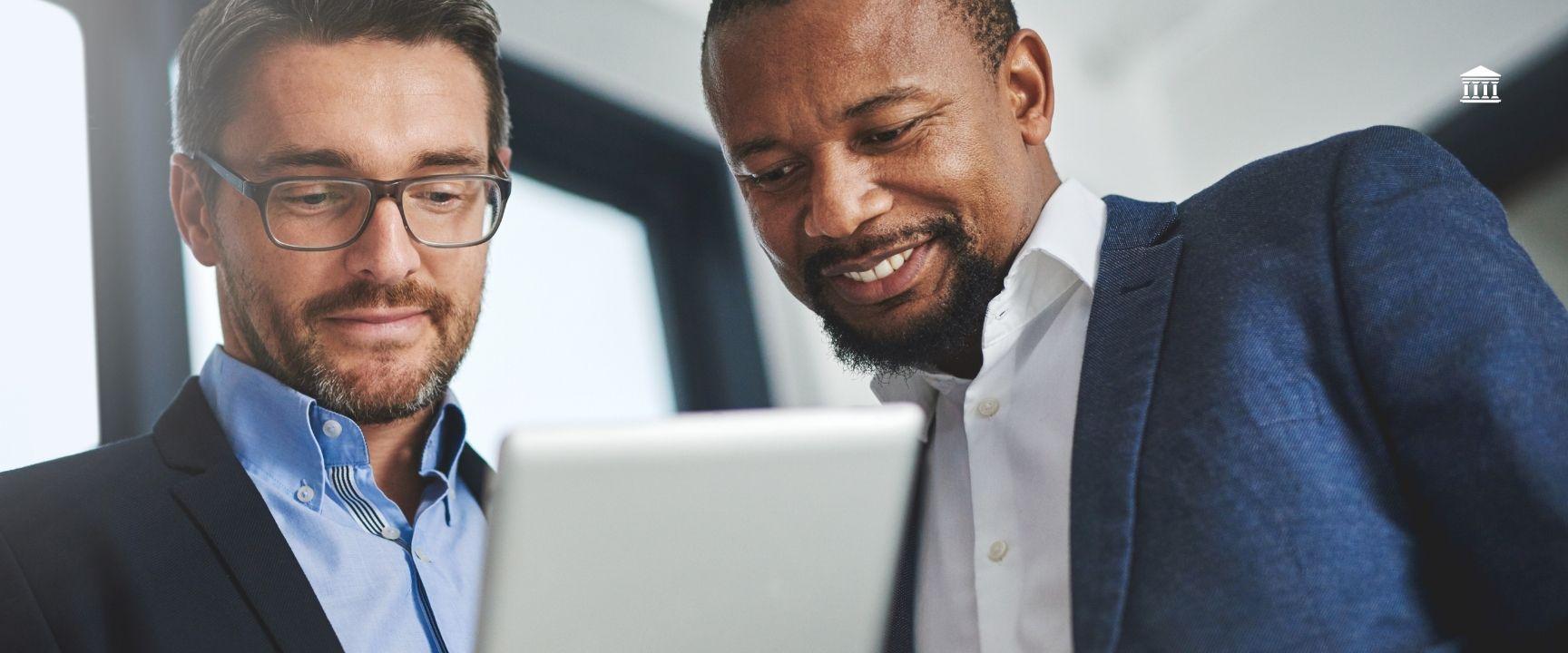 Two investors talking to each other looking at their tablet