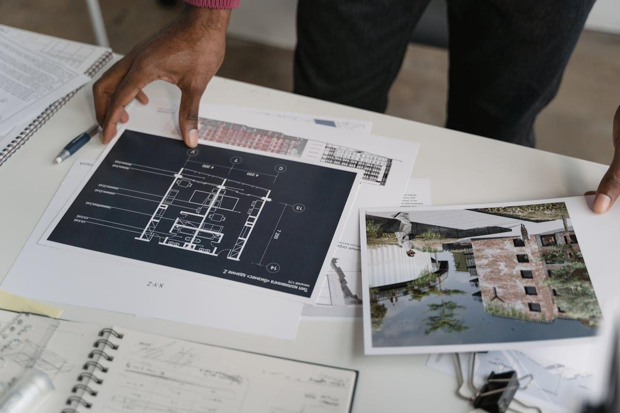 Hands reviewing property plans, floor layouts, and site images, representing transparent evaluation of U.S. real estate investment offerings